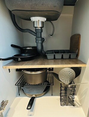 A kitchen with a pot on the stove, a frying pan, a spatula, and a tray of baking molds. - Modern Suite Near Parque 93 | Premium Design & Great Location (Bogotá)