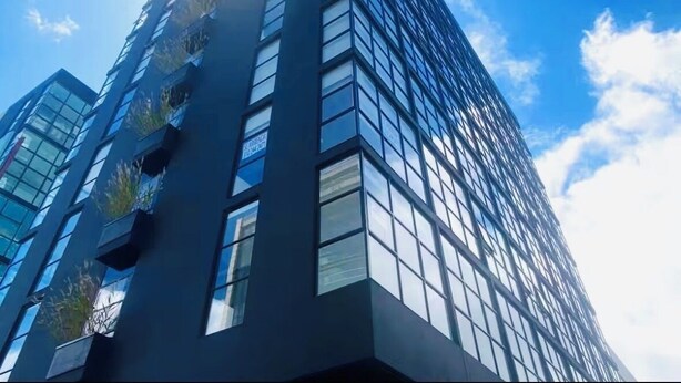 Un immeuble moderne et imposant, doté d’une façade en verre et de nombreuses fenêtres.
