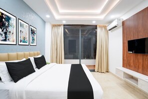 A modern hotel room with a large bed, a flat-screen TV, and artwork on the wall. - Classic With Balcony Sector 51 Gurgaon (Gurugram)
