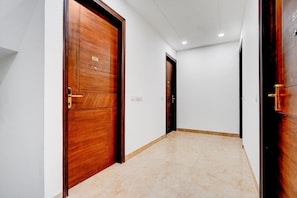 Un passadís amb portes de fusta, un terra de rajola i una paret blanca.