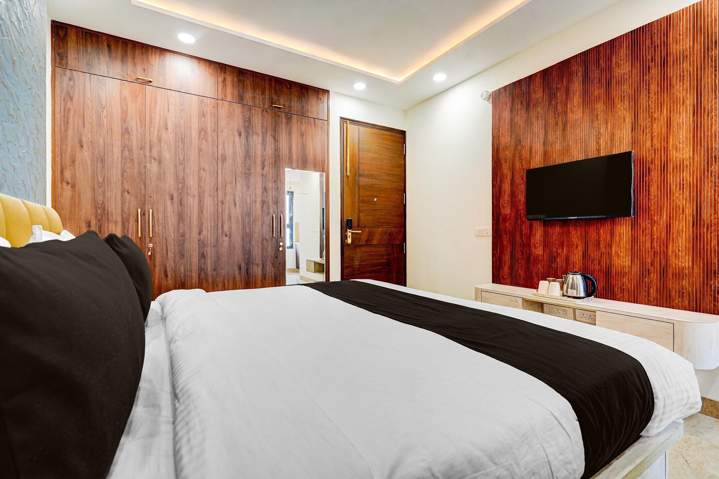 Ein Schlafzimmer mit einem Bett, einem Holzschrank, einem Fernseher und einem kleinen Tisch mit Wasserkocher.