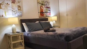 Een slaapkamer met een bed, twee nachtkastjes, een wanddecoratie en een kledingkast.