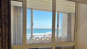 Une chambre d’hôtel dotée d’une grande porte-fenêtre coulissante donnant sur un balcon avec vue sur la mer.