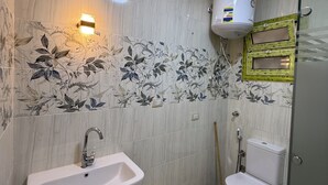 Une salle de bain équipée d’un lavabo, de toilettes, d’une douche et de carreaux décoratifs sur les murs.