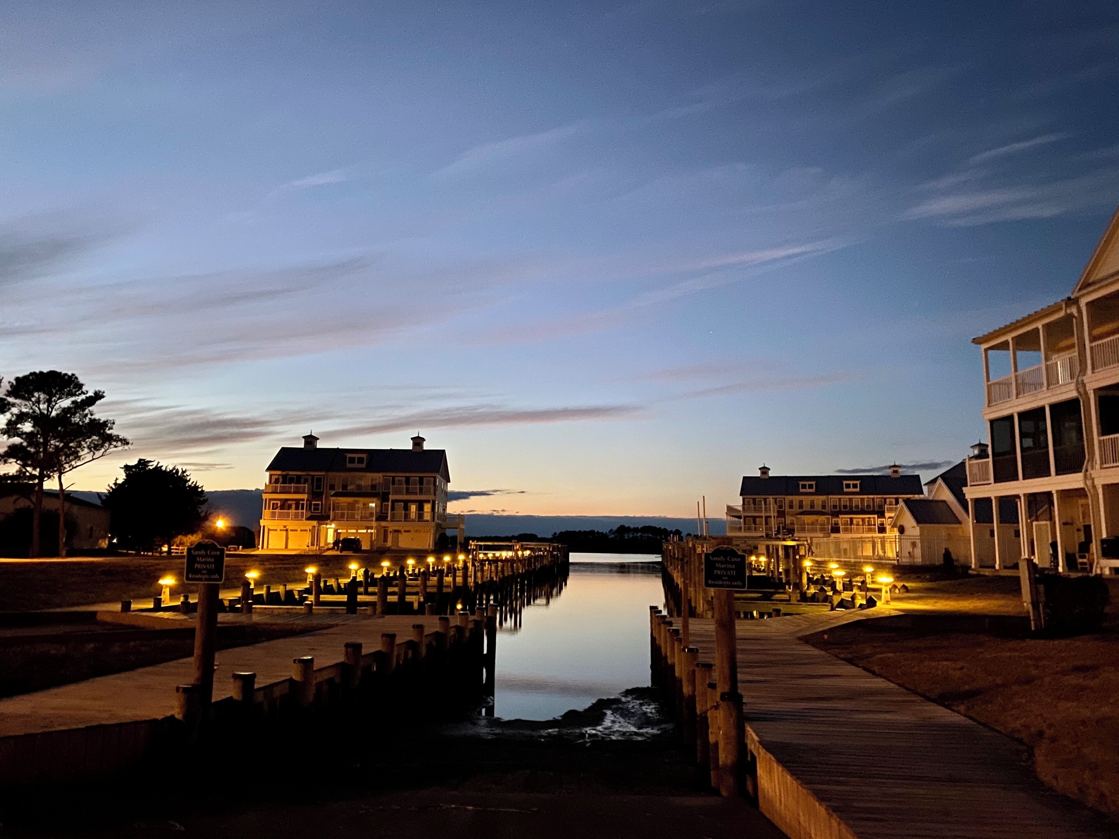 A waterfront property with a wooden pier, a dock, and buildings with multiple stories.