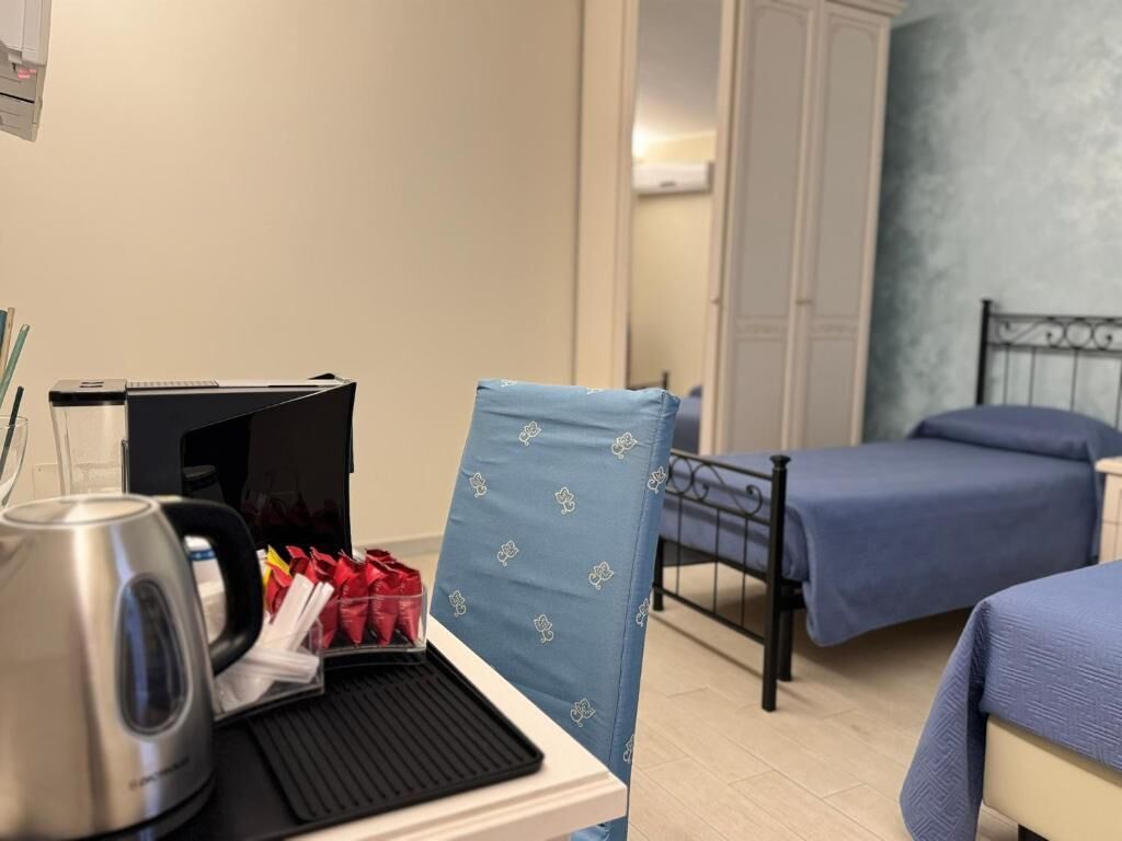 Een hotelkamer met een bed, een bureau met waterkoker, een stoel en een kledingkast.