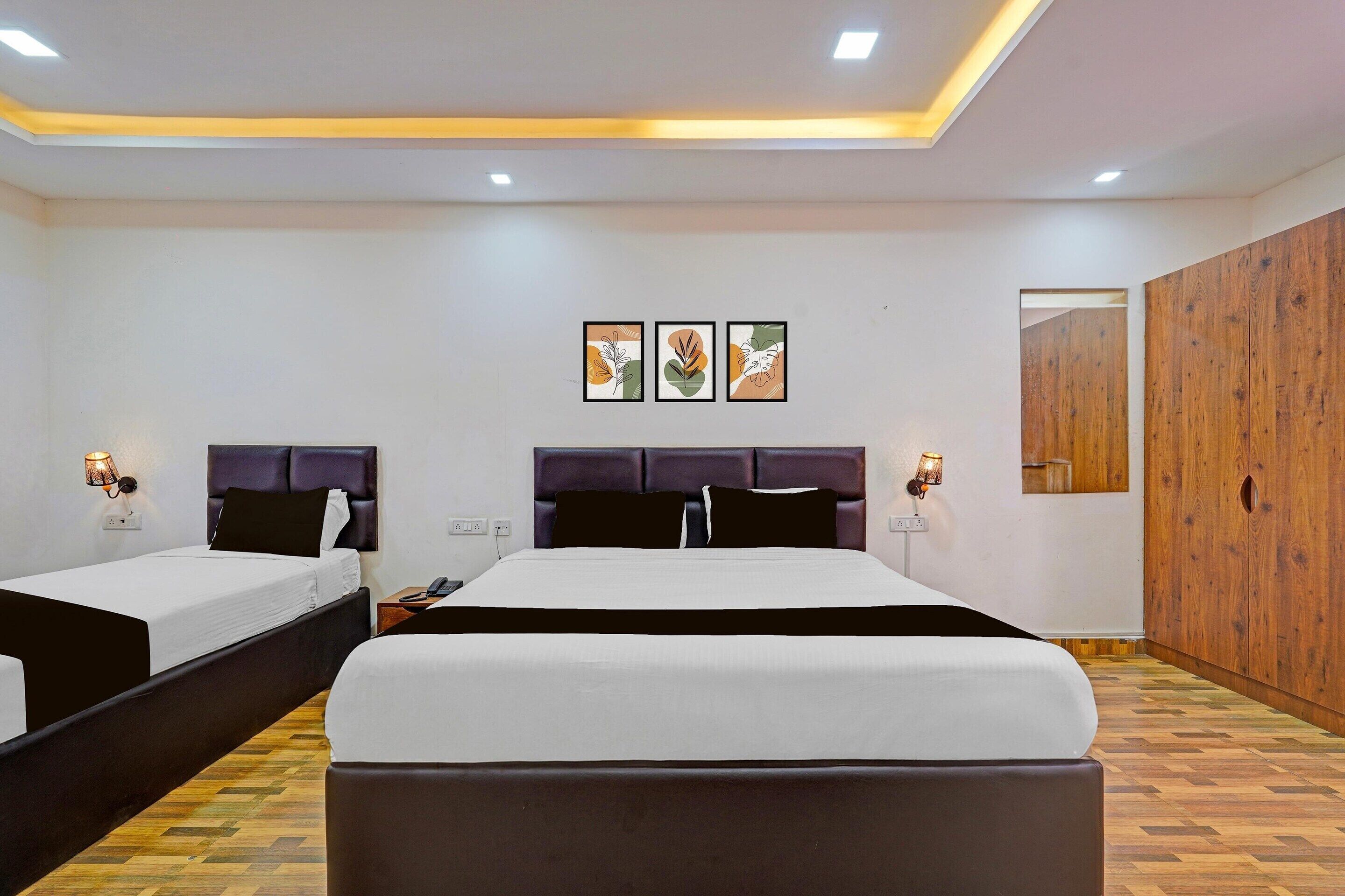 A hotel room with two beds, a wooden wardrobe, and three wall-mounted artworks.