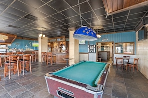 A pool table in a bar area with wooden chairs and a bar counter. - Updated Ocean Front Condo- Sleeps 4! Great amenities! (Myrtle Beach)
