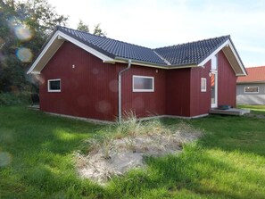 A red building with a sloped roof, a small porch, and a grassy yard. - 4 Star Holiday Home in Grossenbrode (Grossenbrode)