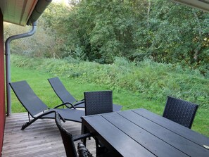 A wooden deck with a table and chairs, surrounded by greenery. - 4 Star Holiday Home in Grossenbrode (Grossenbrode)