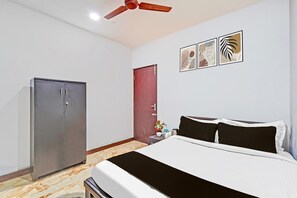 A bedroom with a bed, a wardrobe, a door, and a ceiling fan. - Deluxe spl Palace (Chennai)