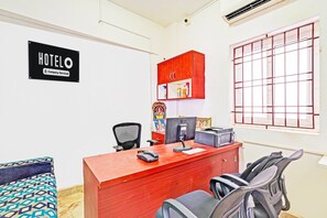 A hotel reception area with a red desk, black office chairs, a computer, and a 'HOTELO' sign on the wall. - Deluxe spl Palace (Chennai)