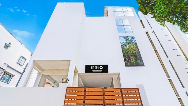 A modern building with a sign reading 'HOTELO' and a wooden gate in front. - Deluxe spl Palace (Chennai)