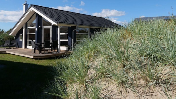 A modern house with a covered patio, large windows, and a sandy surrounding. - 4 Star Holiday Home in Grossenbrode (Grossenbrode)