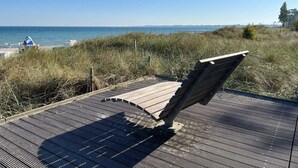 A wooden deck with a bench overlooking a beach. - 4 Star Holiday Home in Grossenbrode (Grossenbrode)