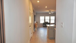 A hallway leading to a kitchen with wooden flooring, a ceiling fan, and a window with blinds. - Modern Townhome • 17 mins from Augusta Masters (North Augusta)