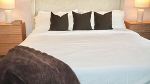 A neatly made bed with white bedding and dark pillows, flanked by two bedside tables with lamps. - Modern Townhome • 17 mins from Augusta Masters (North Augusta)