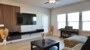 A living room with a flat-screen TV, a piano, a sofa, and a coffee table. - Modern Townhome • 17 mins from Augusta Masters (North Augusta)