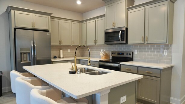 A kitchen with a central island, stainless steel appliances, and light-colored cabinetry. - Modern Townhome • 17 mins from Augusta Masters (North Augusta)