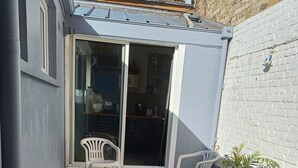 A patio with a tiled floor, a black table, and two white plastic chairs.