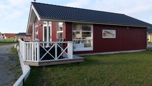 A red building with a white porch and a grey roof. - 4 Star Holiday Home in Grossenbrode (Grossenbrode)
