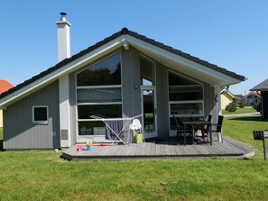 Ein eingeschossiges Haus mit einer breiten Veranda, einem Schornstein und einer Schiebetür.