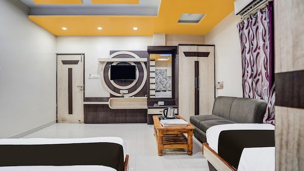 Ein modernes Hotelzimmer mit einer Couch, einem Bett, einem Holztisch und einem großen, runden Kunstwerk an der Wand.