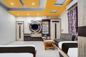 A modern hotel room with a sofa, a bed, a wooden coffee table, and a large circular artwork on the wall. - Suite Townhouse Bihar Sharif (Bihar Sharif)
