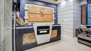 Ein Empfangsschalter mit einer Uhr, einem Schild mit der Aufschrift 'Townhouse' und einer Couch im Hintergrund.