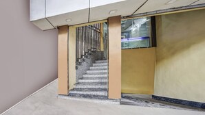 Eine Treppe mit Metallgeländer, sandfarbenen Wänden und einer Glastür zu einem Raum.