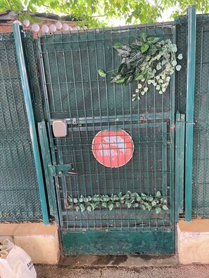 A green metal gate with a red circular sign, a small white object, and some green plants growing on it. - La Terrasse, your cosy nest 10 minutes from train stations, old town and beaches (Antibes)