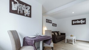 Una sala de estar moderna con comedor, que incluye un sofá, una mesa de comedor con sillas y obras de arte en las paredes.