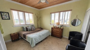 Un dormitorio con cama, cómoda, dos sillas, espejo y ventana.