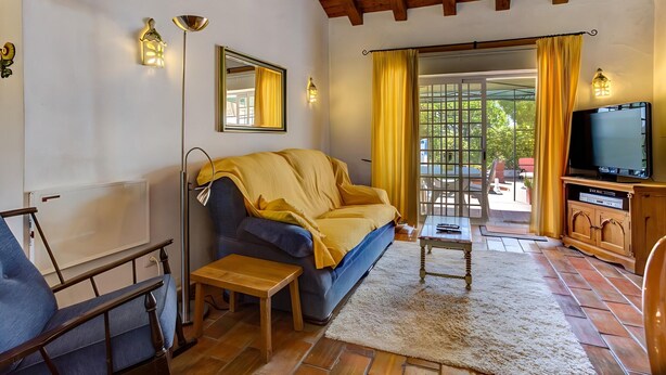 A living room with a sofa, a television, a small table, and a chair. - Algarve Apartment With Garden & Pool (Portimão)