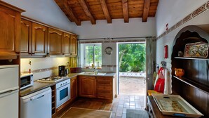 A kitchen with wooden cabinets, a stove, a sink, and a window. - Algarve Apartment With Garden & Pool (Portimão)