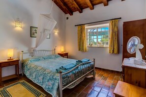 A bedroom with a bed, bedside lamps, a window with curtains, a fan, and a wooden ceiling. - Algarve Apartment With Garden & Pool (Portimão)