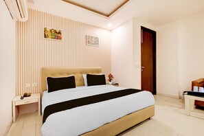 Una camera d'albergo con un letto grande, un comodino con una lampada e una porta in legno.