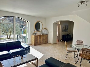 A modern living room with a sofa, coffee table, dining table, and chairs. There is a large window, a mirror, and a cabinet. - House in the heart of nature, between wildlife and the good life! (Mondragon)