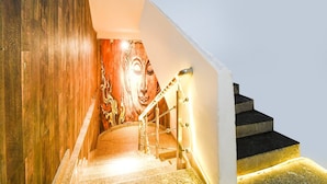 A staircase with wooden walls and a mural, leading to a landing with a handrail and steps. - Super Deluxe Room Super Collection O (Gobindpur)