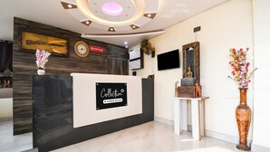 A reception area with a modern design, featuring a reception desk, a clock, a television, and decorative items. - Super Deluxe Room Super Collection O (Gobindpur)