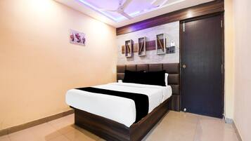 A bedroom with a bed, a ceiling fan, a dark door, and a wall-mounted shelf with decorative items.
