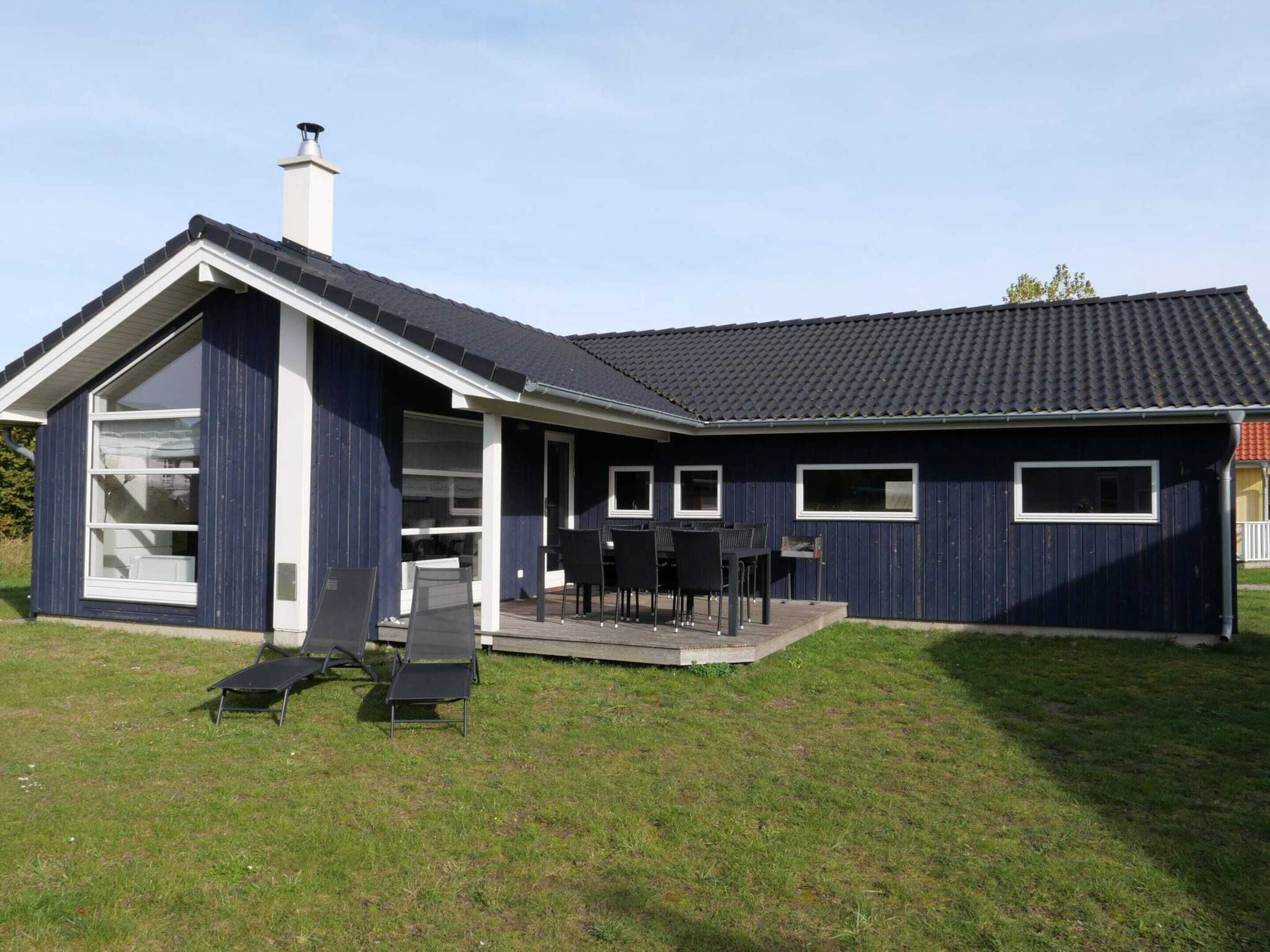 A modern house with a large deck, a chimney, and a garage.
