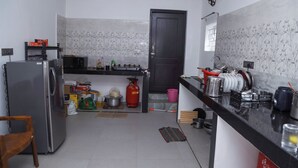 Uma cozinha equipada com geladeira, micro-ondas, fogão a gás e diversos utensílios.