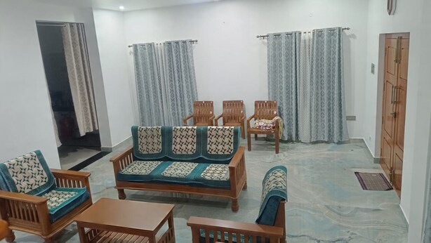 Uma sala de estar com sofá, cadeiras, uma mesa e cortinas.