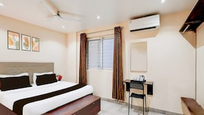 A bedroom with a bed, a desk, a chair, an air conditioner, a ceiling fan, and a window with curtains. - Single Room Olivia Comforts (Bengaluru)