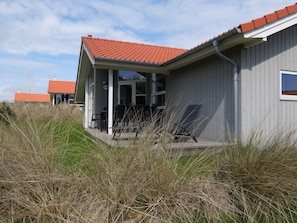 En bygning med røde tegltage, en overdækket veranda med stole og et skilt med nummer 114.