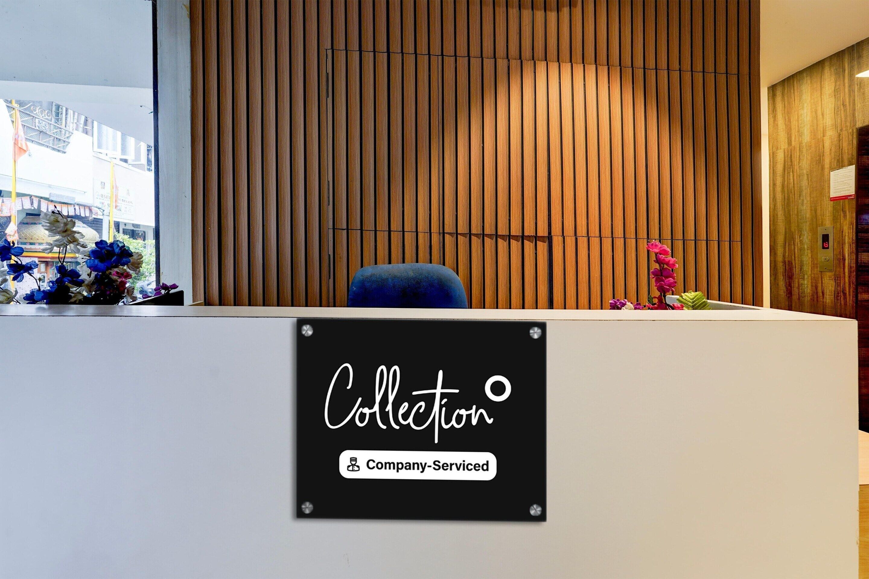 Een receptiebalie met een bord waarop 'Collection' en 'Company-Serviced' staan.