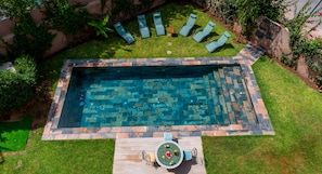 A rectangular swimming pool with a stone border, surrounded by a grassy area with lounge chairs. - Flextay - VILLA Lounge - 4Ch - Pool - Billiards (Marrakesh)