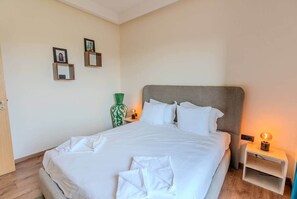 A neatly made bed with white linens, a green vase, and two framed pictures on the wall. - Flextay - VILLA Lounge - 4Ch - Pool - Billiards (Marrakesh)