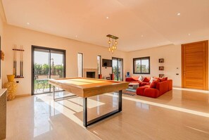 A modern living room with a pool table, red sofa, and a large wooden door.